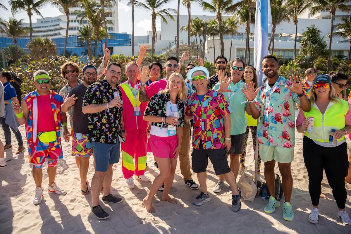 Group of adults dressed in neon posing for a photo at the beach